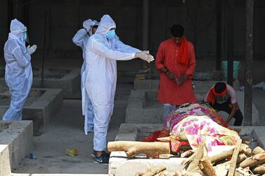 A family member wearing protective gear performs the final rites of a coronavirus victim at a crematorium in New Delhi. AFP