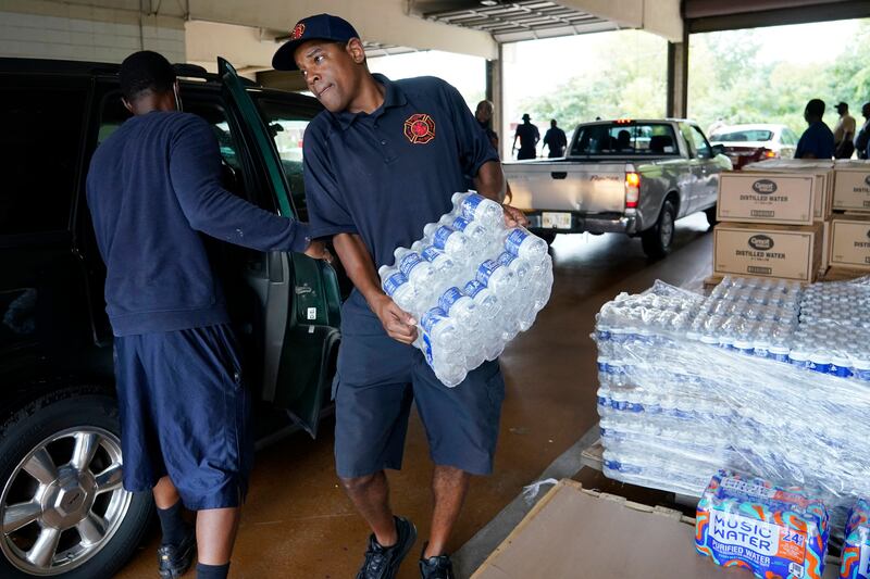 A Jackson Fire Department firefighter puts cases of bottled water into a resident's car as part of the city's response to water system problems. AP