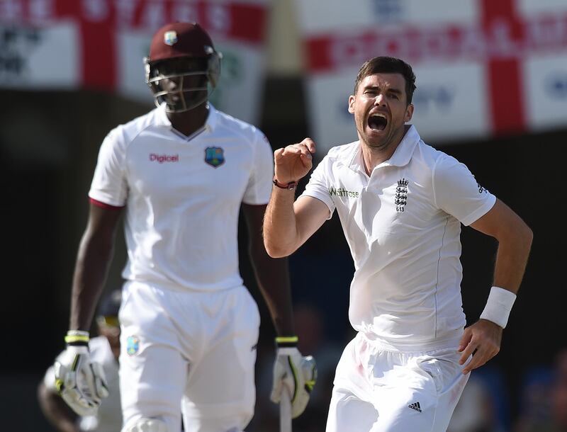 English fast bowler James Anderson (R) celebrates beside West Indies batsman Jason Holder after becoming the highest ever English wicket taker with 384 after taking the wicket of West Indies captain Denesh Ramdin on day five of the first cricket Test match between West Indies and England at the Sir Vivian Richards Stadium in St John's, Antigua on April 17, 2015.  Anderson has taken the record from previous holder Ian Botham on 383.         AFP PHOTO/ MARK RALSTON (Photo by MARK RALSTON / AFP)