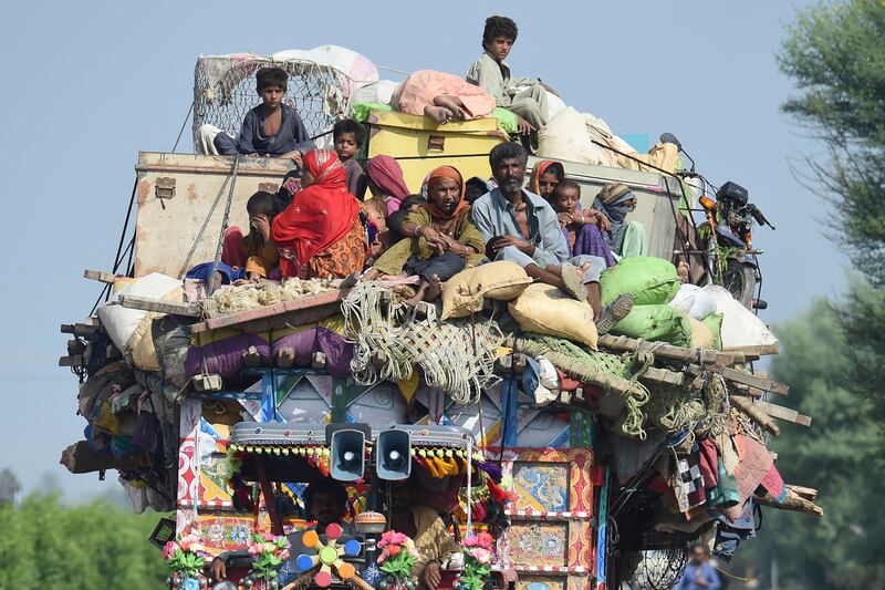 People make their way to safer ground after flooding from monsoon rains hit homes in Shikarpur, Pakistan. AFP