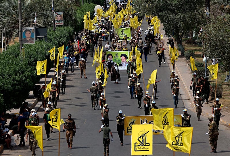 Iraqi Popular Mobilization Forces march as they hold Popular Mobilization flags and posters of Shiites spiritual leaders during "al-Quds" Day, Arabic for Jerusalem, in Baghdad, Iraq, Friday, June 8, 2018. Jerusalem Day began after the 1979 Islamic Revolution in Iran, when the Ayatollah Khomeini declared the last Friday of the Muslim holy month of Ramadan a day to demonstrate the importance of Jerusalem to Muslims. (AP Photo/Hadi Mizban)