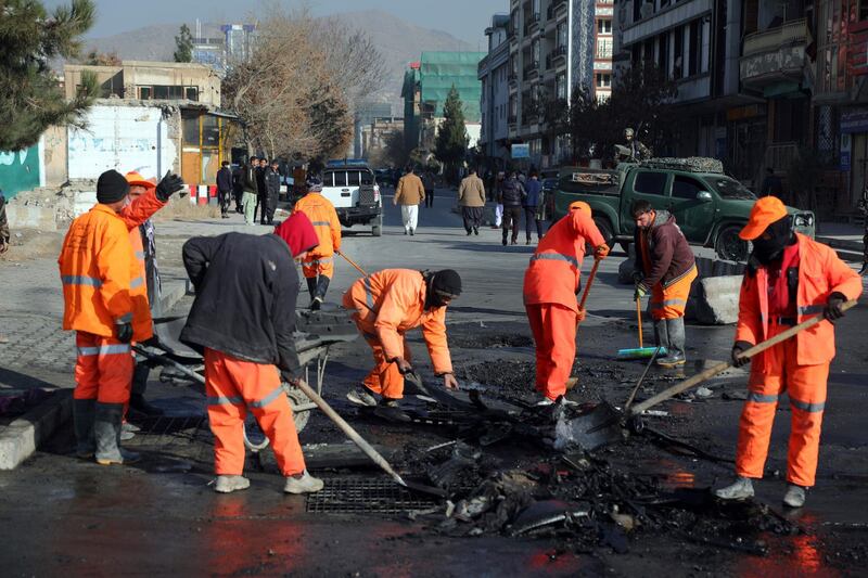 Afghan municipality workers clean the remains of a vehicle after a bomb blast in Kabul, Afghanistan, Sunday, December 13, 2020. AP