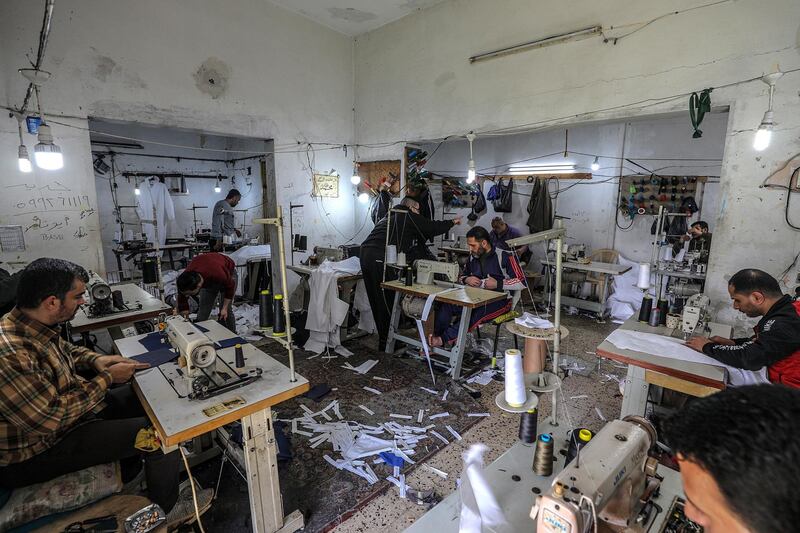Palestinians manufacture protective coverall suits to shield against coronavirus, in a small sewing factory in Gaza City, on March 30, 2020.  EPA