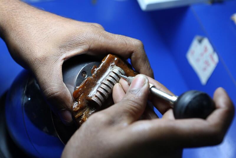 A craftsman sets precious stones on gold jewellery at Damas' new factory. Pawan Singh / The National