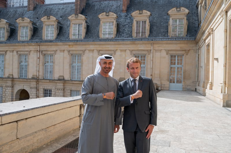 Sheikh Mohamed and President Macron pose for a photograph wearing Expo 2020 Dubai wristbands.