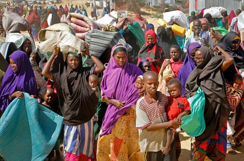 FILE - In this Saturday, May 18, 2019 file photo, people fleeing from drought in the Lower and Middle Shabelle regions of Somalia carry their belongings as they reach a makeshift camp for displaced persons in the Daynile neighborhood on the outskirts of the capital Mogadishu. On Tuesday, June 5, 2019, a United Nations emergency relief coordinator said more than 2 million men, women and children could die of starvation in Somalia by summer's end if international aid is not sent quickly to the drought-stricken African country. (AP Photo/Farah Abdi Warsameh)