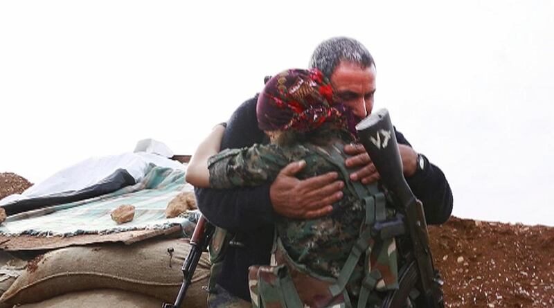 In this image made from a video taken in late November, 2014, Kurdish fighter Pervin Kobani, 19, and her father, Farouk, embrace in Kobani, Syria. Jake Simkin via AP video