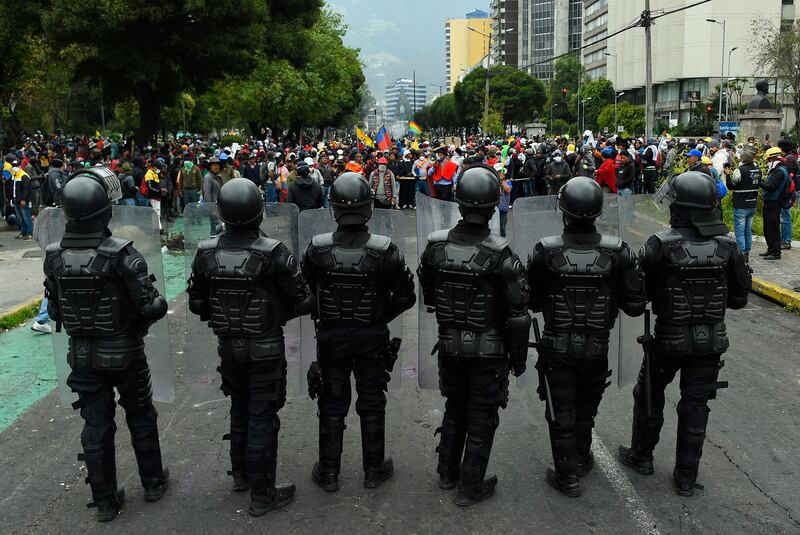 Police officers stand guard as indigenous people gather in El Arbolito park area in Quito on the 10th day of protest against Ecuador's government. AFP