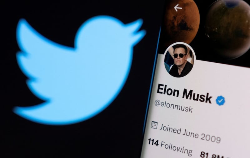 Elon Musk's twitter account is seen on a smartphone in front of the Twitter logo. Reuters