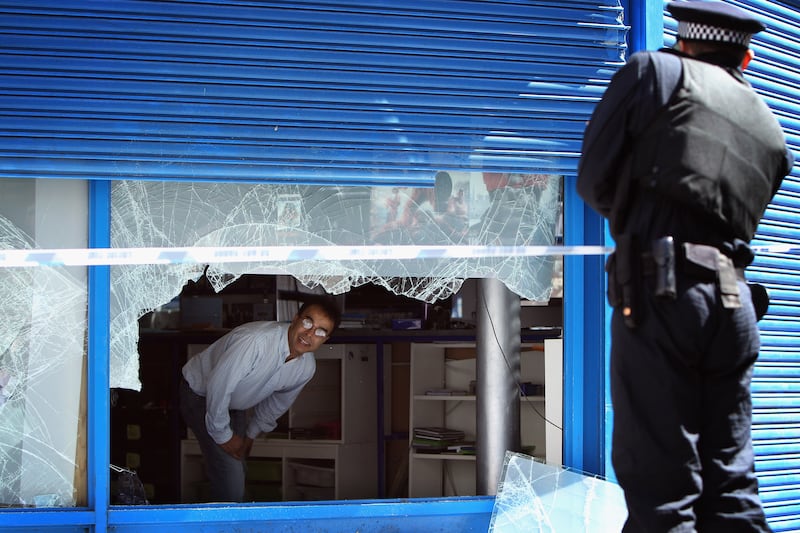 A shopkeeper speaks to a police officer in Brixton after looting took place.