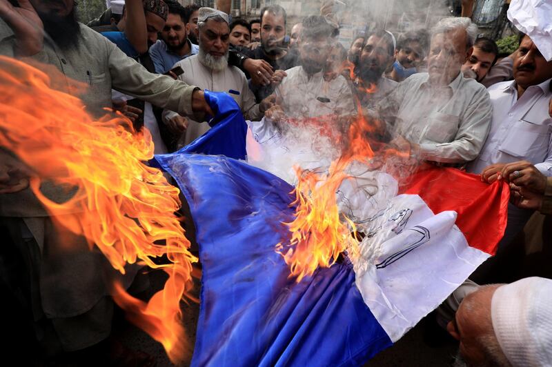 People chant slogans as they set fire to a France's flag during a protest against the cartoon publications of Prophet Mohammad in France and comments by the French President Emmanuel Macron, in Peshawar, Pakistan October 28, 2020. REUTERS/Fayaz Aziz