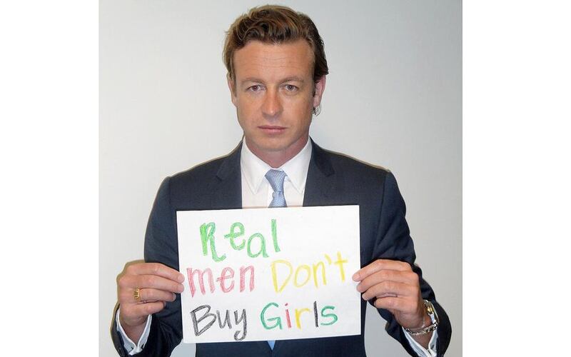Simon Baker holds up a sign reading Real Men Don’t Buy Girls. Courtesy Simon Baker