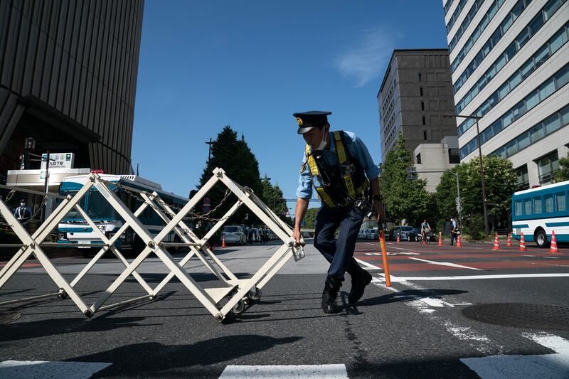 A police officer prepares to close a gate on a road near the funeral venue, Nippon Budokan in Tokyo. Getty 