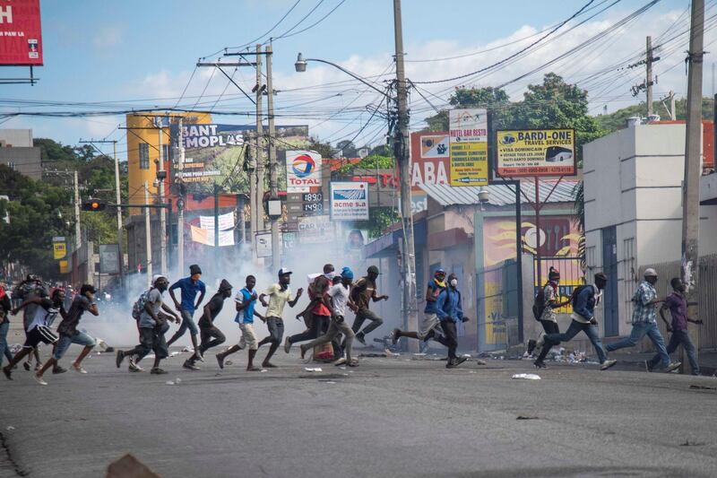 People run down a street during a protest in Port-au-Prince. EPA