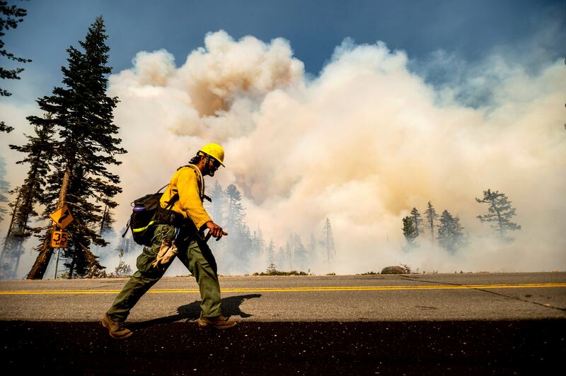 A firefighter battles the Dixie Fire along Highway 89 in Lassen National Forest, California, the US.