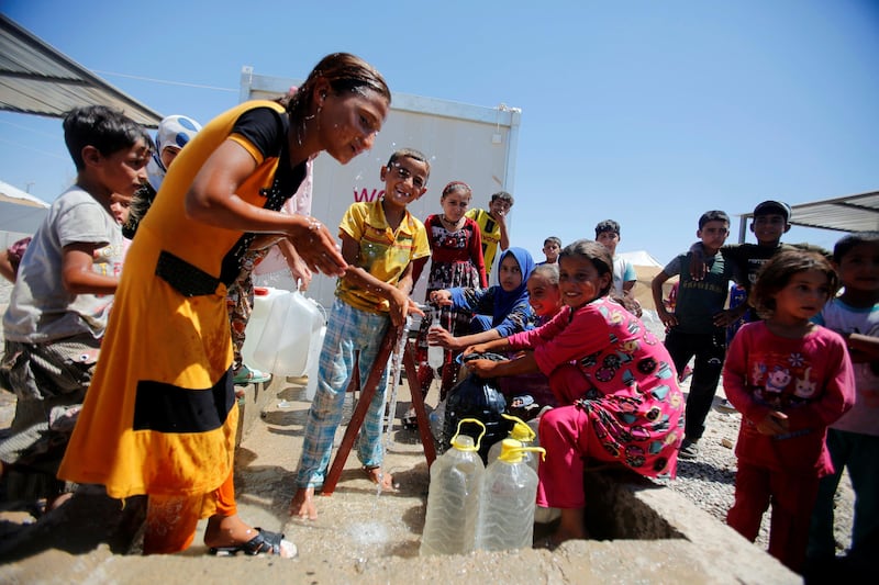 Displaced people who fled their homes fill bottles with water at Salamiyah camp, near Mosul, Iraq August 6, 2017. REUTERS/Khalid al Mousily