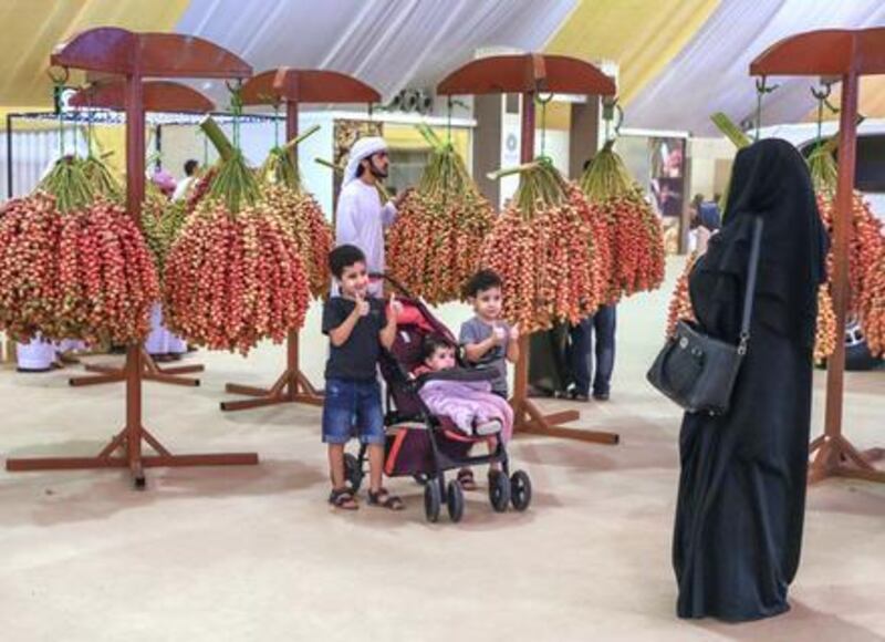 Visitors of the Liwa Date Festivals take photos besides large bunches on display on opening day. Victor Besa / The National