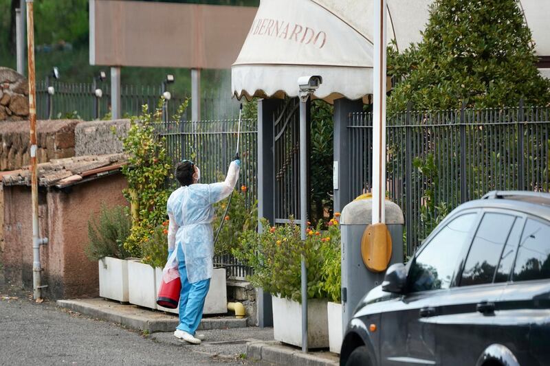 A woman sanitises the entrance of the Casa San Bernardo hotel, in Rome, Italy. AP