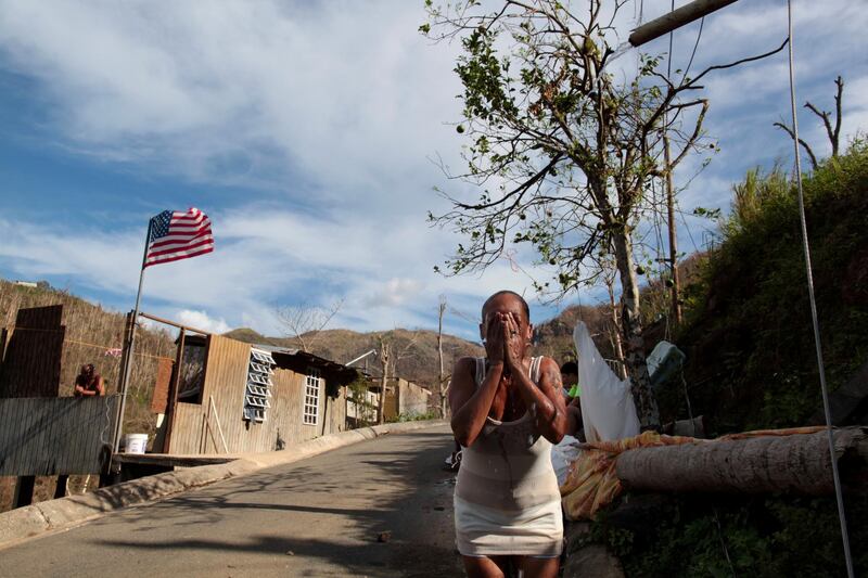 Ruth Santiago refreshes herself with water from a pipe after Hurricane Maria destroyed the town's bridge in San Lorenzo, Morovis, Puerto Rico, on October 4, 2017. Reuters