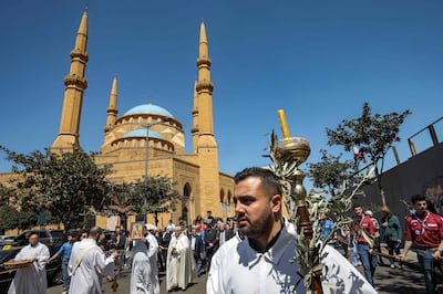 A deacon marches with a candle and olive branches in a procession outside Mohammed Al Amin Mosque at Martyrs' Square, Beirut, on Palm Sunday. AFP
