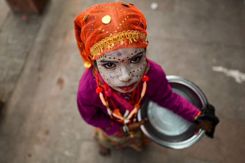 A child wearing make-up while asking for alms from passers-by at a market area ahead of Diwali in New Delhi. AFP