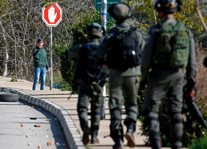 A Palestinian youth gestures to Israeli soldiers in Ramallah. AFP