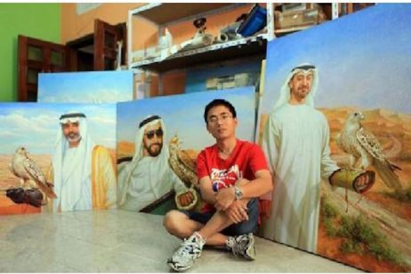 Jack Lee, a Chinese expatriate, pictured in his studio in Abu Dhabi with three examples of his work. He describes himself as a “realistic” painter.  Ravindranath.K / The National