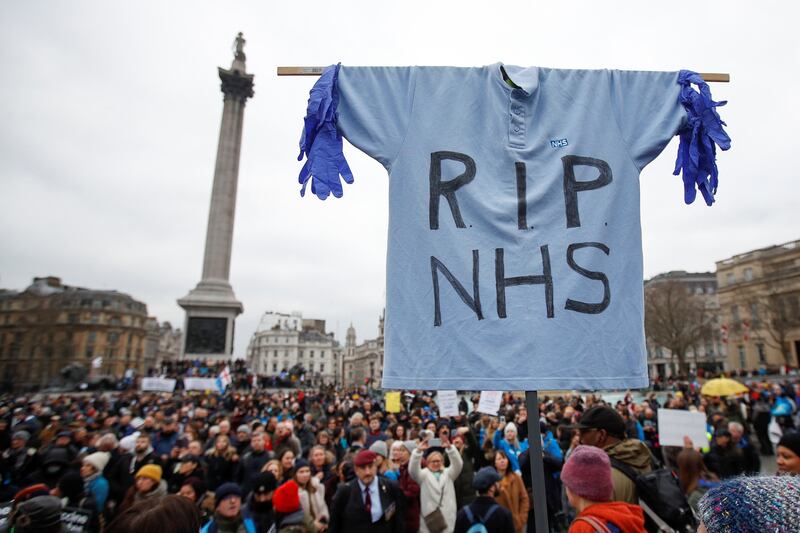 National Health Service workers carry an NHS polo shirt with a slogan written across it during a protest against vaccine rules in Trafalgar Square, central London. Reuters