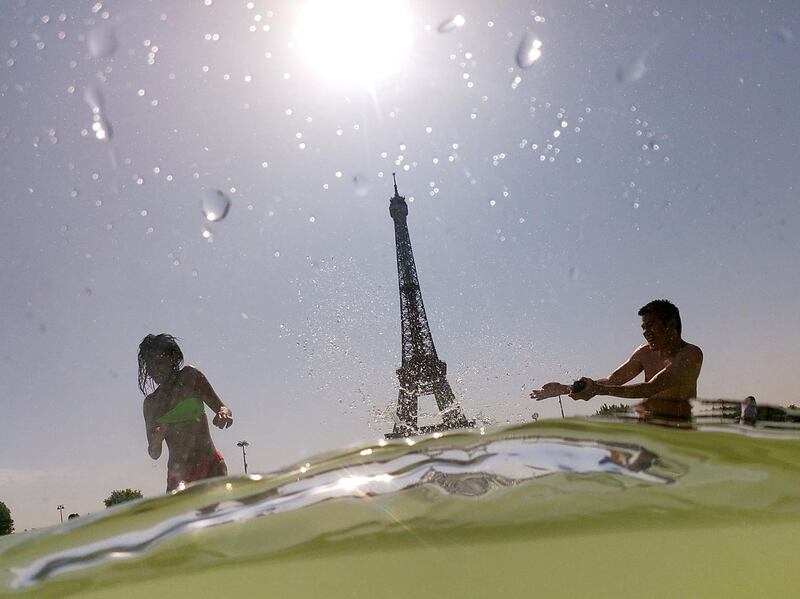 People cool off at the Trocadero Fountains next to the Eiffel Tower in Paris.  AFP