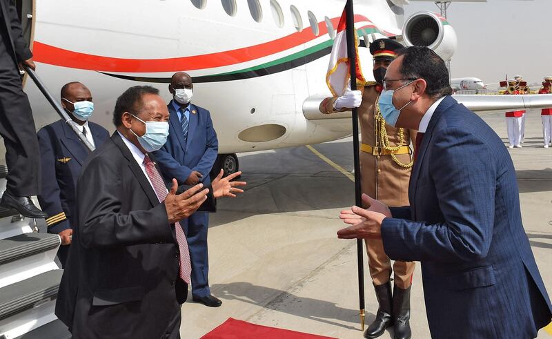 Egyptian Prime Minister Mostafa Madbouly (R) welcomes his Sudanese counterpart Abdalla Hamdok upon his arrival in the Egyptian capital Cairo, on March 11, 2021.  Sudan, Egypt and Ethiopia have been locked for almost a decade in inconclusive talks over the filling and operation of the Grand Ethiopian Renaissance Dam (GERD) on the Blue Nile, which broke ground in 2011.  / AFP / Selman Elotefy
