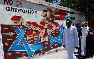 Hamas supporters pass a mural against Israel's plan to annex parts of the West Bank and U.S. President Donald Trump's mideast initiative, after Friday prayer's protest at the main road of Rafah refugee camp, Gaza Strip, Friday, July 3, 2020. (AP Photo/Adel Hana)