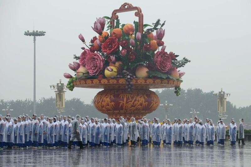 People queue up in front of a giant vase in Tiananmen Square prior to a wreath-laying ceremony marking the 64th anniversary of founding of the People's Republic of China. Ed Jones / AFP Photo