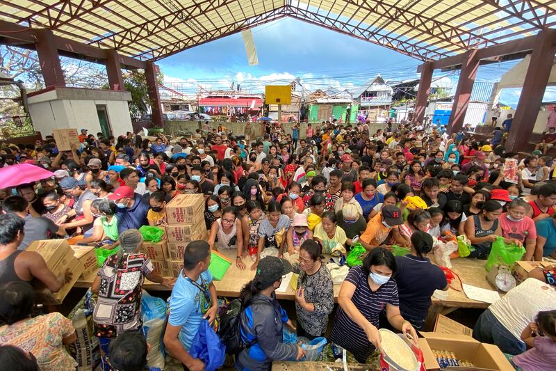 Filipinos hit by Typhoon Rai gather as relief goods are distributed in Surigao City. Reuters