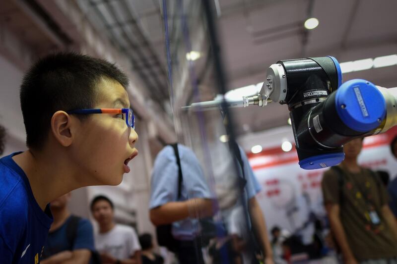 A boy looks at a robot arm at the 2018 World Robot Conference in Beijing on August 15, 2018. AFP