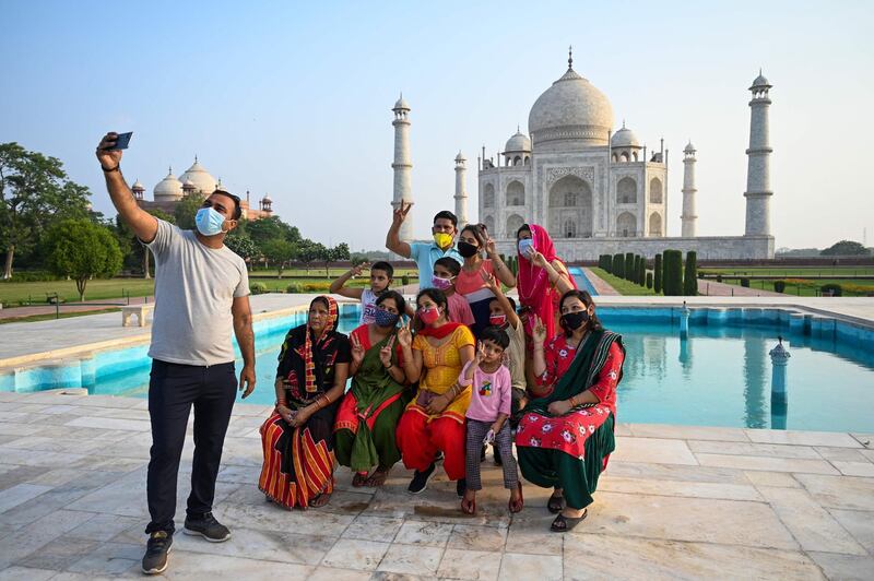 A group of tourists take souvenir photos at the Taj Mahal after it reopened to visitors. AFP