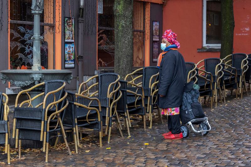 A woman passes by an empty terrace in the Marrolles quarter in Brussels, Belgium. AP Photo