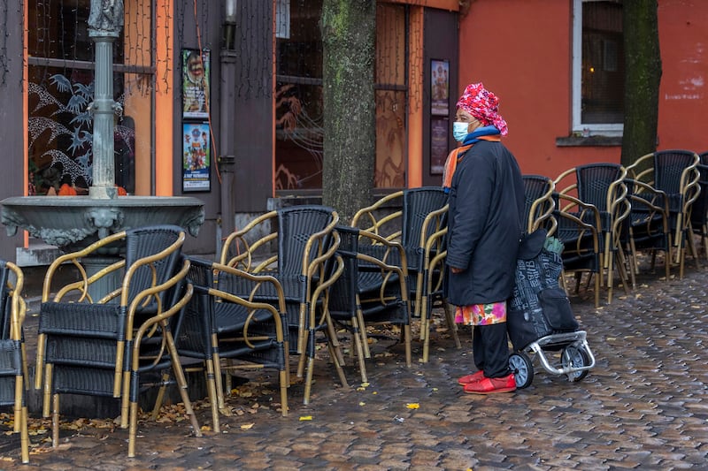 A woman passes by an empty terrace in the Marrolles quarter in Brussels, Belgium. AP Photo