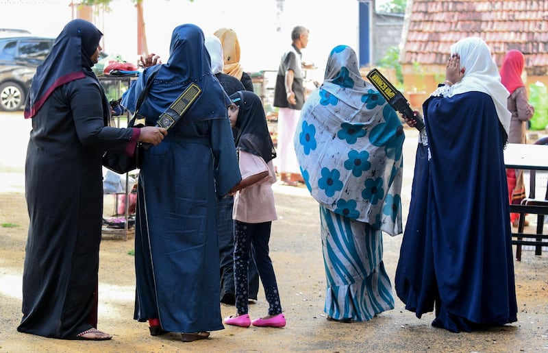 Sri Lankan Muslim women search devotees at the entrance of the Grand Mosque on the first day of Eid al-Fitr in Colombo on July 5, 2019. - Muslims around the world are celebrating the Eid al-Fitr festival, which marks the end of the fasting month of Ramadan. (Photo by LAKRUWAN WANNIARACHCHI / AFP)