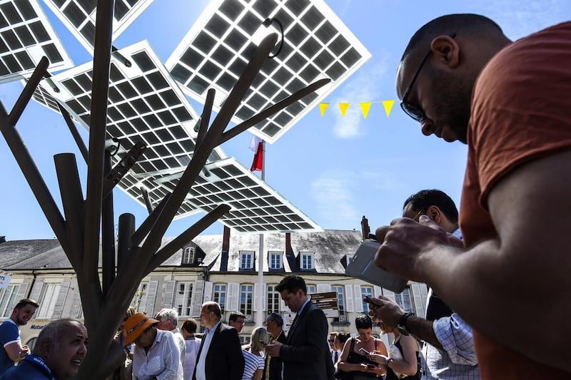 People connect their smart-phones to the first "eTree" provided in Europe. Via its photovoltaic foliage, users can recharge cell phones, surf the internet or recharge an electric bike. The tree also distributes fresh water and lights up at night. Philippe Desmazes / AFP