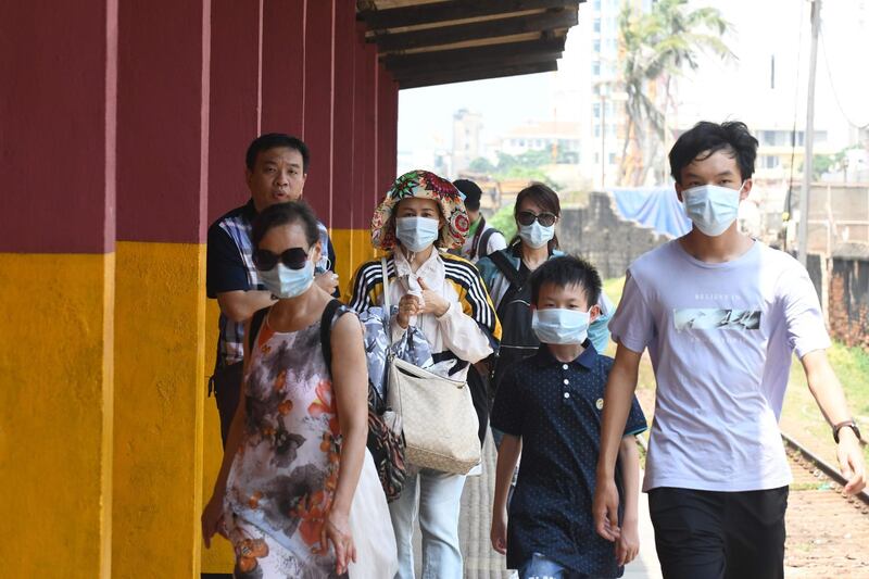 Chinese tourists wearing protective masks to help stop the spread of a deadly virus which began in Wuhan, look on at a train station in Colombo.  AFP