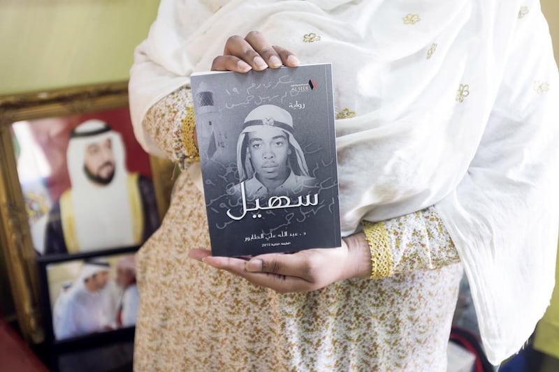 Aisha, the niece of UAE's first martyr Salem Suhail bin Khamis Al Dahmani, holds a biography publication about her martyred uncle. Reem Mohammed / The National