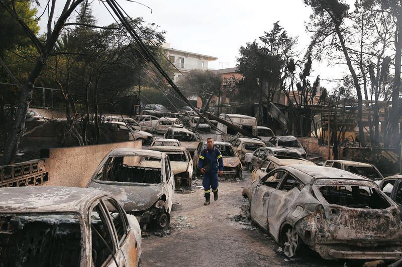 A firefighter walks among burned cars, following a wildfire at the village of Mati. Reuters