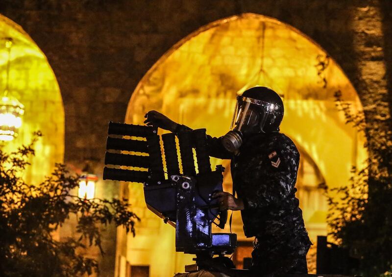 A Lebanese police officer throws tear gas grenades at protesters during clashes in central Beirut.  EPA