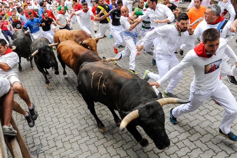 PAMPLONA, SPAIN - JULY 13:  Revellers run with Nunez del Cuvillo's fighting bulls during the eighth day of the San Fermin Running of the Bulls festival  on July 13, 2017 in Pamplona, Spain. The annual Fiesta de San Fermin, made famous by the 1926 novel of US writer Ernest Hemmingway entitled 'The Sun Also Rises', involves the daily running of the bulls through the historic heart of Pamplona to the bull ring. (Photo by Gari Garaialde/Getty Images)
