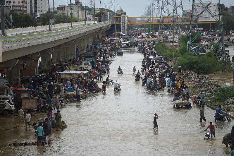 People make their way through a flooded street in Karachi.  AFP