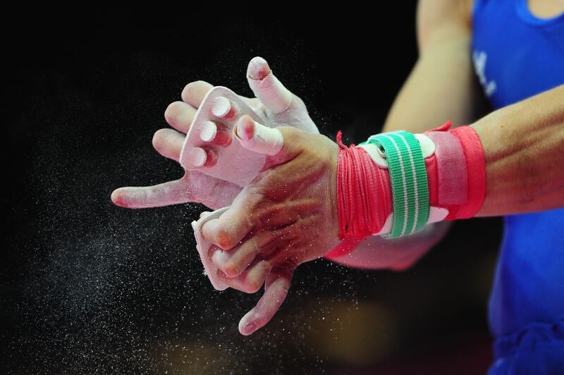 LONDON, ENGLAND - JULY 25:  An athlete chalks his hands before praciticing on the parallel bars ahead of the London Olympic Games at the North Greenwich Arena on July 25, 2012 in London, England.  (Photo by Mike Hewitt/Getty Images)