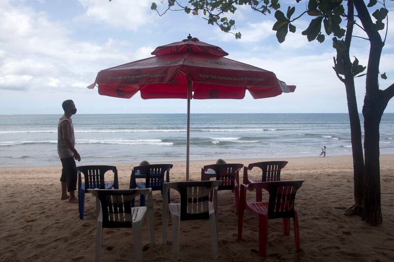 A beach vendor sets chairs as he waits for customers in Kuta beach in Bali, Indonesia. AP Photo