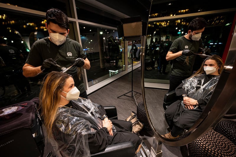 The first customer of Shan Rahimkhan's barbershop gets her hair cut and colored after the reopening in Berlin. AP Photo