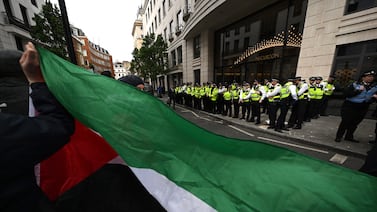 Pro-Palestinian protesters hold a flag as they stand opposite police officers in central London. Getty Images