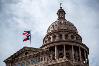 The US and Texas state flags fly over the state Capitol building on July 12, 2021 in Austin, Texas. AFP